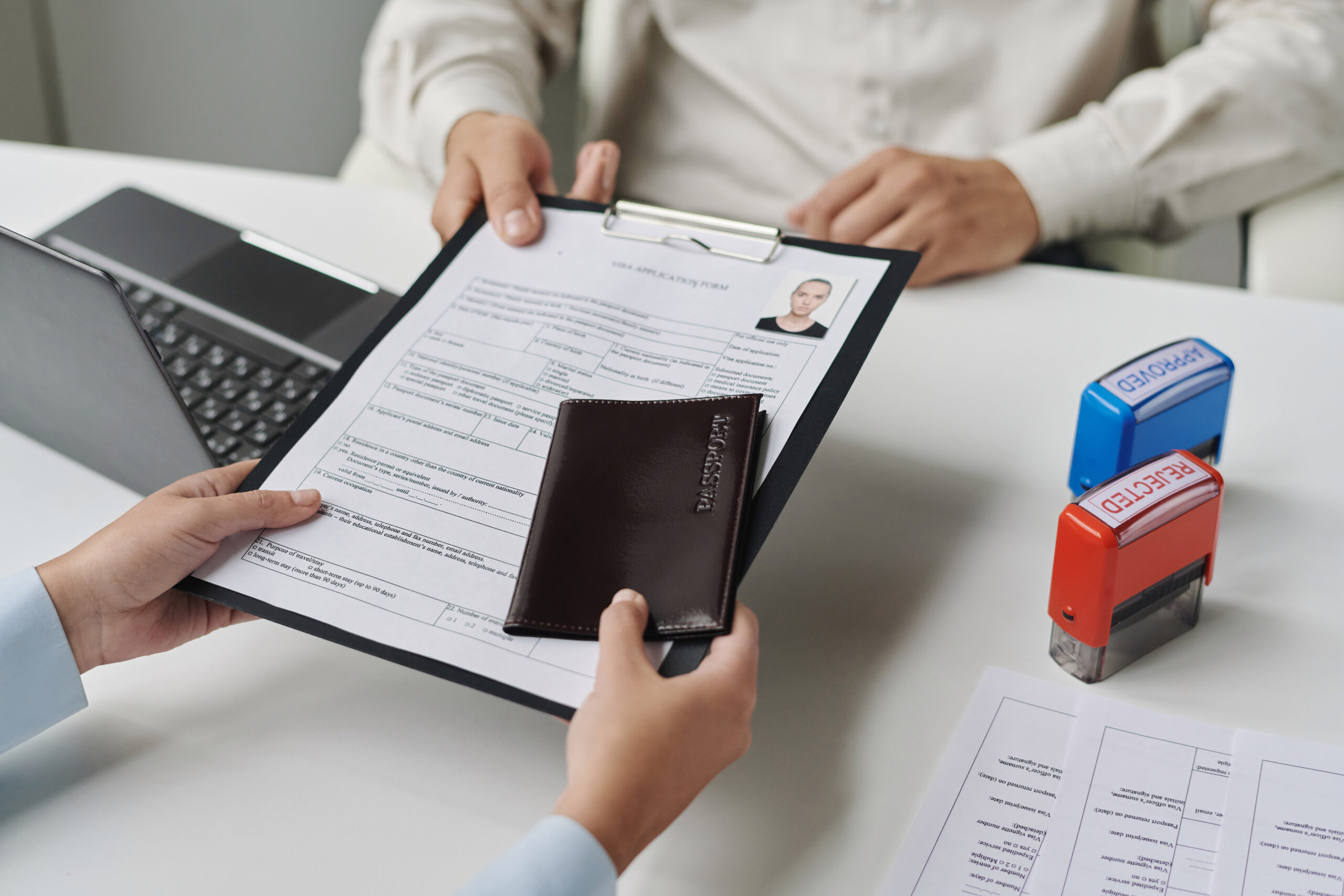 Close-up of woman giving documents to get visa in visa center