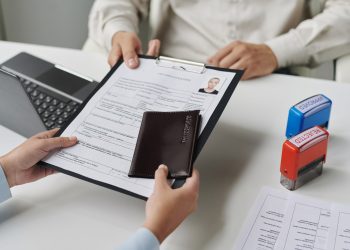 Close-up of woman giving documents to get visa in visa center